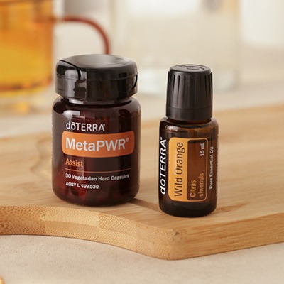 doTERRA MetaPWR Assist capsules and Wild Orange 15mL essential oil on a wooden board